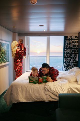 A family enjoys a cosy Christmas breakfast in their cabin, with a stunning sea sunrise visible from the balcony | MSC Cruises