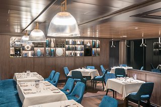A spacious restaurant with elegant tables and blue chairs ready to welcome guests for a delightful dining experience | MSC Cruises
