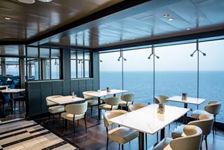 Ein geräumiges Restaurant mit Panoramablick auf das Meer und den Himmel, ausgestattet mit Tischen und Stühlen für Gäste | MSC Cruises