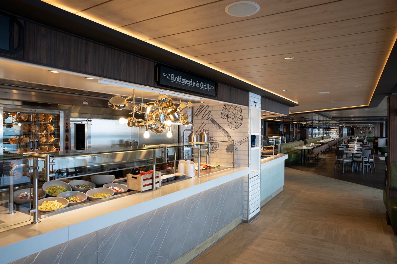 A spacious restaurant area featuring a buffet with various food options, inviting tables and chairs for guests | MSC Cruises