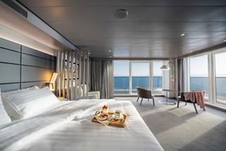 Eine geräumige Grand Suite Aurea mit einem Doppelbett, Balkon und Panoramameerblick, die einen ruhigen Rückzugsort schafft | MSC Cruises