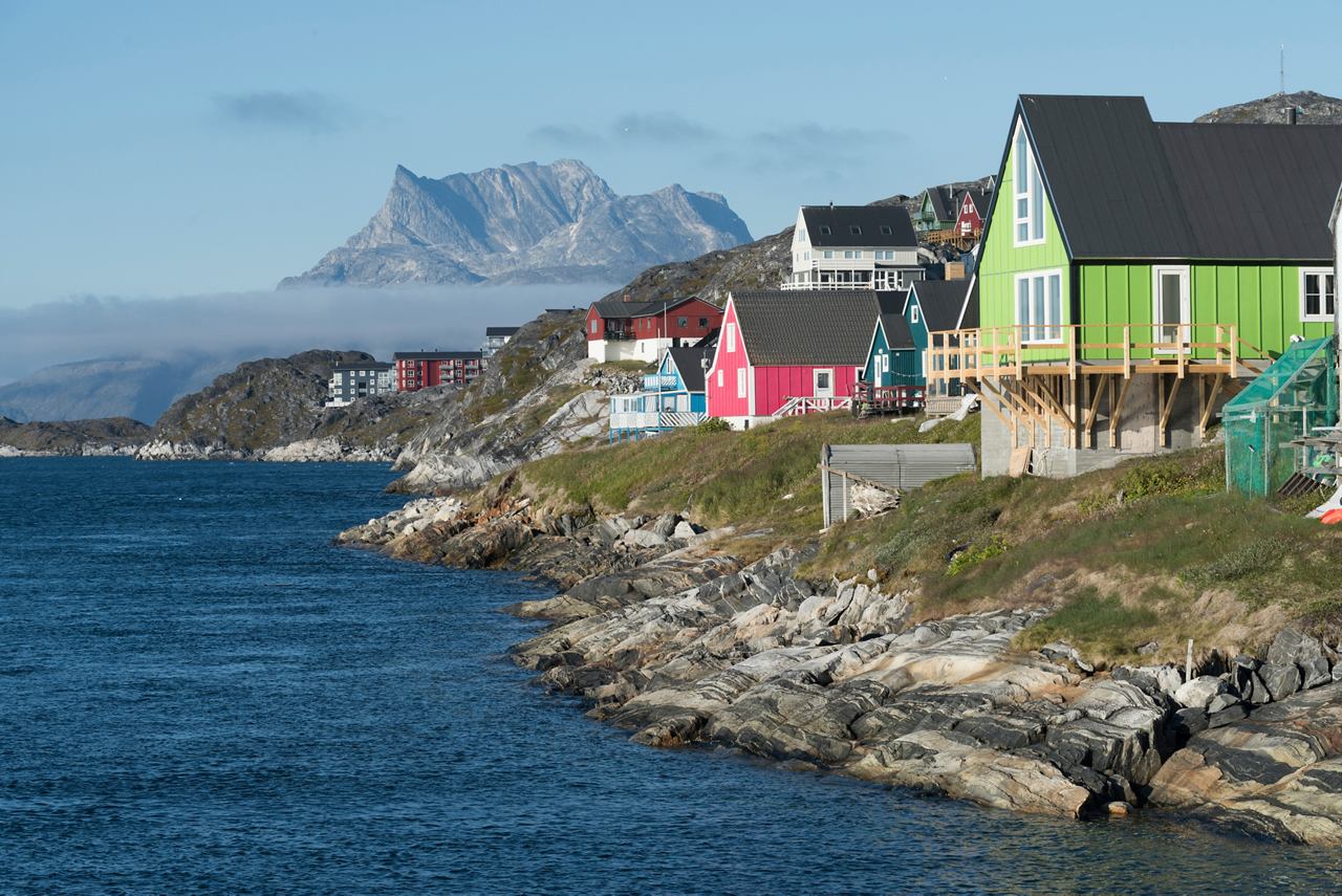 Colourful houses line the rocky coastline of Nuuk, Greenland, with mountains rising majestically in the background | MSC Cruises
