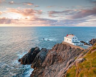 A breathtaking view of a lighthouse perched on a cliff overlooking the sea in Northern Europe | MSC Cruises