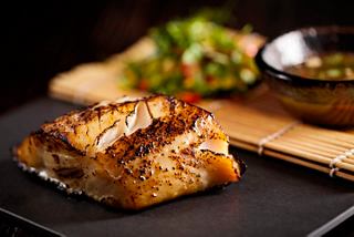 Miso black cod served with a fresh salad and sauce, showcasing Japanese culinary excellence | MSC Cruises