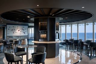 A stylish lounge area with elegant seating and panoramic windows offering stunning ocean views | MSC Cruises