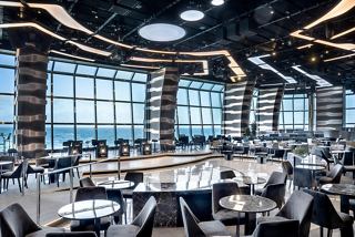 Eine moderne Lounge mit Panoramablick auf das Meer, eleganten Sitzgelegenheiten und einer Bühne für Unterhaltung | MSC Cruises