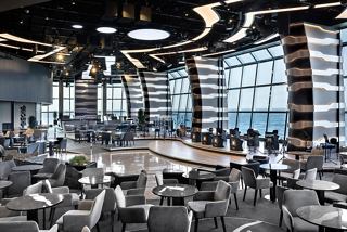 Ein lebendiger Lounge-Bereich mit modernen Sitzgelegenheiten und großen Glaswänden, die atemberaubende Ausblicke auf das Meer und den Himmel bieten | MSC Cruises