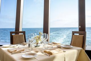 A beautifully set dining table with a stunning sea view through large glass windows | MSC Cruises