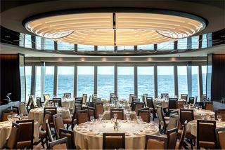 A spacious restaurant with elegant tables and chairs, featuring a stunning sea view through large glass walls | MSC Cruises