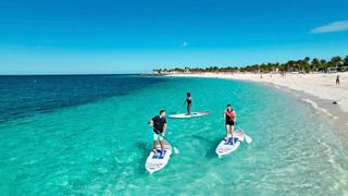 Tre amici fanno paddleboarding nelle chiare acque turchesi di Ocean Cay, circondati da una spiaggia incontaminata | MSC Crociere