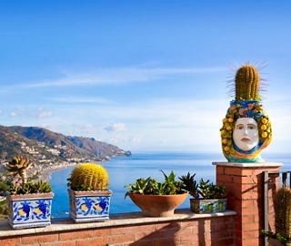 Una vibrante vista costera desde Taormina con elementos decorativos que miran al sereno mar Mediterráneo | MSC Cruceros