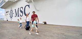 A family joyfully embarks on an MSC cruise, carrying luggage with excitement for their adventure together | MSC Croisières