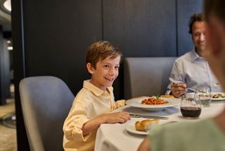 Ein kleiner Junge genießt eine Mahlzeit mit seinem Vater im Ocean Cay Restaurant an Bord der MSC Seashore | MSC Cruises