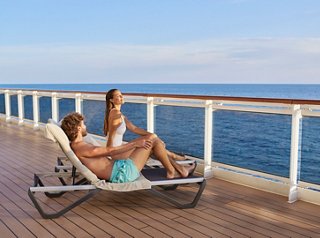 Ein Paar entspannt sich auf Liegen auf dem Deck der MSC Seashore und genießt die Aussicht auf den Ozean und die Sonne | MSC Cruises
