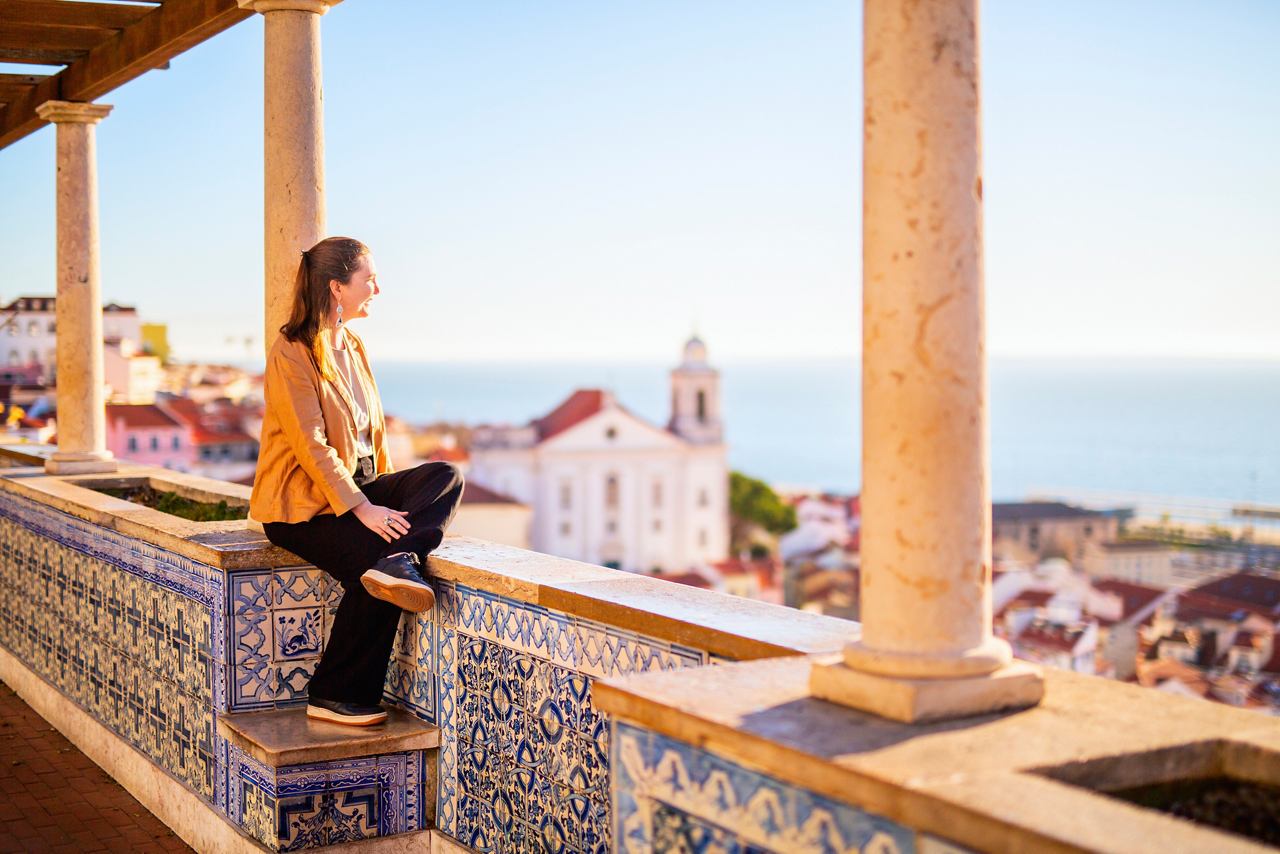 A woman enjoys a panoramic view of the sea and architecture while sitting on a balcony in Funchal, Portugal | MSC Cruises