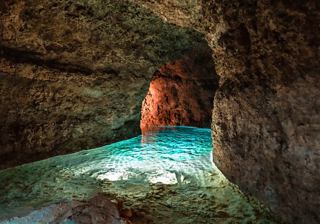 Wasserweg in der Harrison-Höhle mit strahlend blauem Wasser und Licht, das durch die Felsen strömt | MSC Cruises
