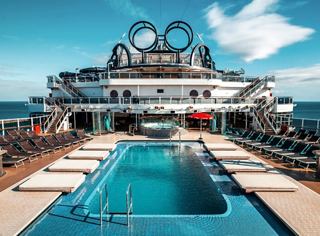 A serene view of the MSC Seaside deck featuring a pool, sun loungers, and the vast ocean in the background | MSC Cruises