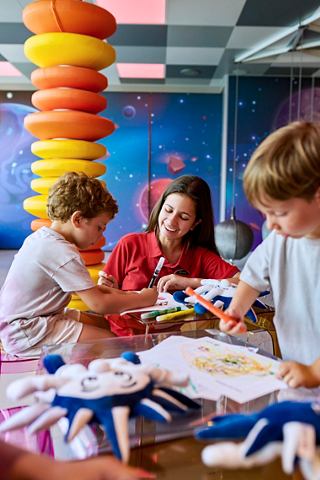 Des enfants dessinent et jouent avec un adulte dans une aire de jeux colorée | MSC Croisières