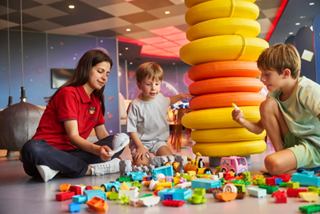 Los niños juegan con bloques de colores, construyendo torres con la ayuda de un adulto | MSC Cruceros