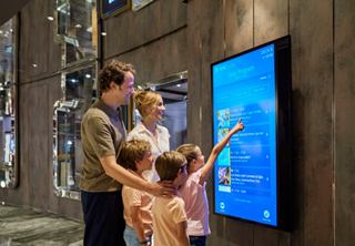 A family engages with a touchscreen display to explore daily programmes and activities on MSC Seashore | MSC Cruises
