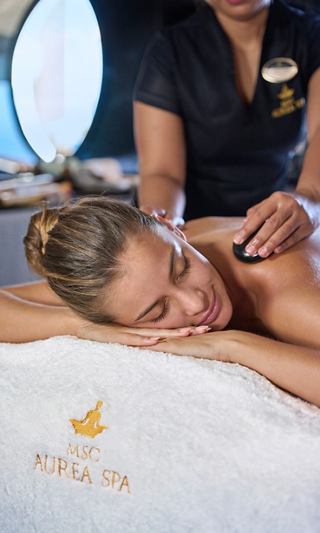 Eine Frau genießt eine entspannende Massage im MSC Aurea Spa, umgeben von einer ruhigen Atmosphäre | MSC Cruises
