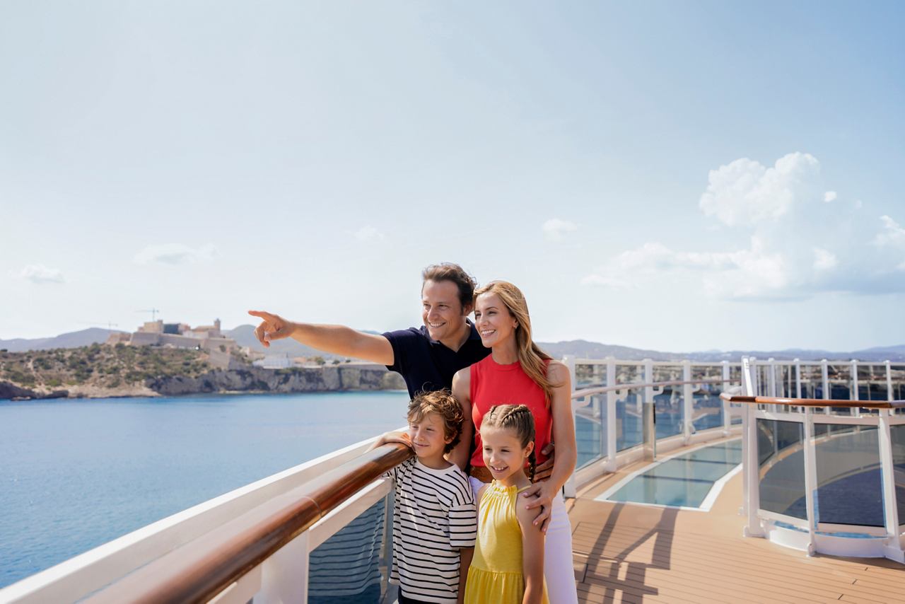 A couple enjoying the view from a ship's balustrade, pointing at the scenic coastline of Ibiza | MSC Cruises