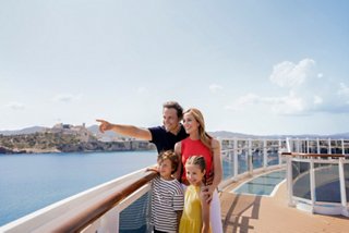 Una coppia gode della vista dalla balaustra di una nave, indicando la suggestiva costa di Ibiza | MSC Crociere