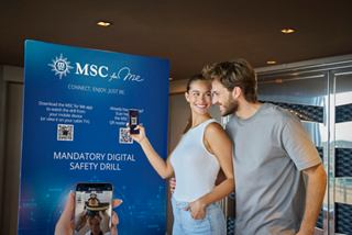 A couple engaging with a digital display while using a smartphone for MSC for Me information | MSC Cruises