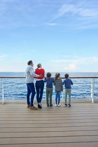 Une famille se tient ensemble sur le pont du MSC Seashore, profitant de la belle vue sur la mer et de l'air frais | MSC Croisières