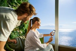 A couple enjoys the sea view while using a smartphone onboard | MSC Cruises