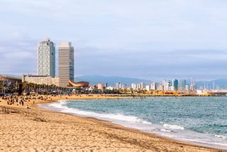 Vue de la plage de Barceloneta avec des bâtiments en arrière-plan, illustrant l'atmosphère côtière dynamique de Barcelone | MSC Croisières