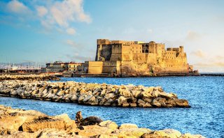 Le château historique Castel dell'Ovo se dresse fièrement le long de la côte de Naples sous un ciel lumineux | MSC Croisières