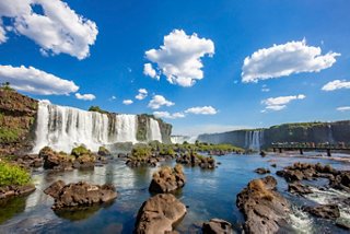 The stunning Iguazu Falls in Argentina surrounded by lush greenery and a bright blue sky | MSC Cruises