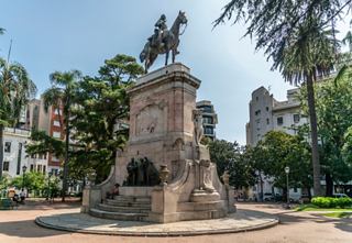 A historic statue of General Don Bruno de Zabala stands proudly in a vibrant square surrounded by trees and benches | MSC Cruises