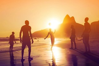 Un groupe de garçons joue au football sur la plage lors d'un coucher de soleil vibrant | MSC Cruises