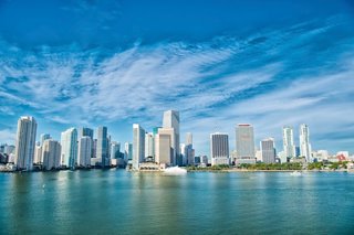 Lo skyline vibrante di Miami si riflette nel mare calmo sotto un cielo azzurro brillante | MSC Crociere