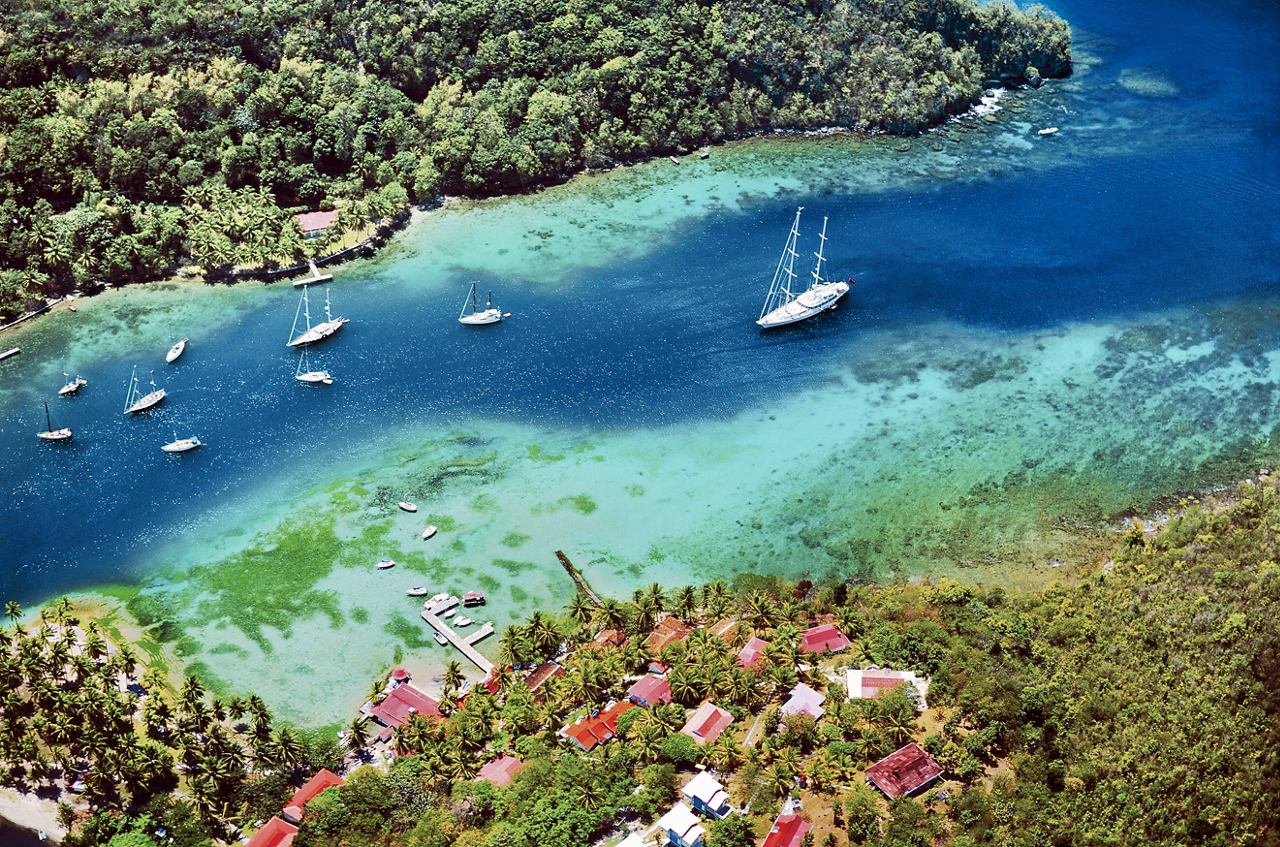 Vue aérienne de la baie de Marigot présentant une végétation luxuriante, un port serein et des bateaux dans les eaux turquoise | MSC Croisières