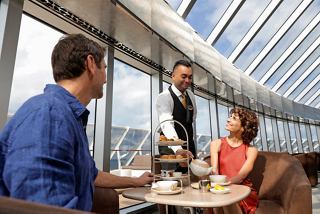 Un couple profite d'un délicieux service de thé d'un serveur dans le cadre élégant du MSC Yacht Club | MSC Croisières