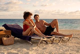 A couple relaxes on sunbeds by the beach at sunset, enjoying the serene atmosphere of Ocean Cay | MSC Cruises