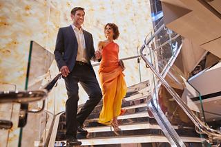 Un couple élégamment vêtu se tient sur un escalier dans le MSC Yacht Club, profitant de son temps à bord du MSC Seashore | MSC Croisières