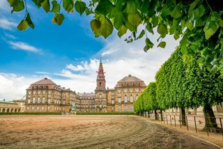 A view of Christiansborg Palace with lush trees and a clear sky in Copenhagen, Denmark | MSC Cruises