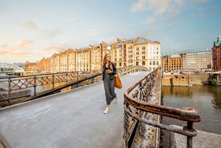 A woman strolls across a scenic bridge in Hamburg, with charming buildings and a river in view under a bright sky | MSC Cruises
