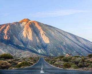 A scenic view of Teide Volcano in Tenerife, surrounded by greenery and a clear road leading towards it | MSC Cruises