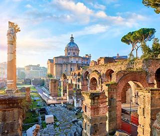 View of Rome's historic landmarks, including the Colosseum and church dome, under a sunny sky | MSC Cruises
