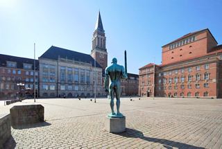 A scenic view of Kiel's City Hall and square, featuring a prominent tower and a decorative monument | MSC Cruises