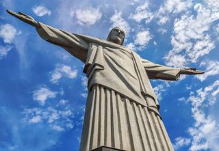 Christ the Redeemer statue stands majestically against a bright blue sky with clouds, symbolising hope and unity | MSC Cruises