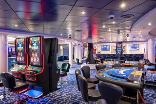 A vibrant casino area featuring gaming tables, slot machines, and a stylish bar for entertainment on MSC Opera | MSC Cruises