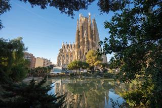 La straordinaria facciata della Sagrada Familia circondata da verde e riflessa in uno stagno | MSC Crociere