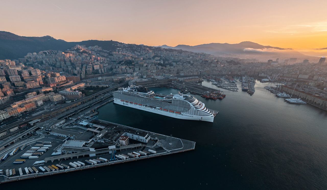 Luftaufnahme der MSC World Europa, die in Genua, Italien, liegt, umgeben von Meer und Bergen bei Sonnenaufgang | MSC Cruises