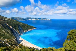 A panoramic view of Myrtos Beach in Cefalonia, showcasing the vibrant sea and lush coastline under a blue sky | MSC Cruises